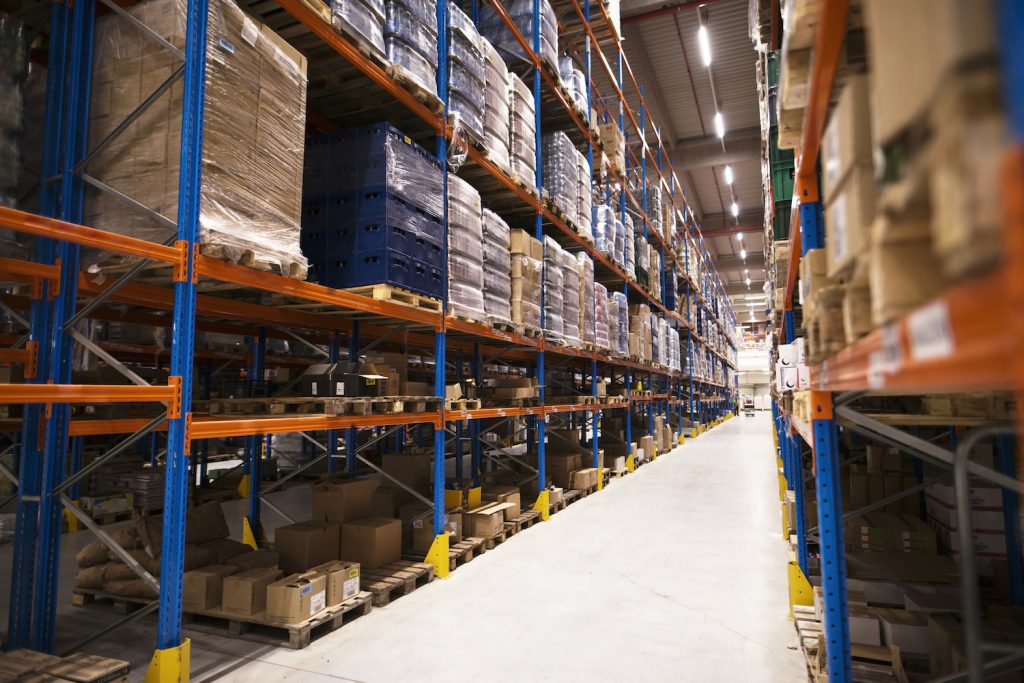 Puertas rápidas Interior of large distribution warehouse with shelves stacked with palettes and goods ready for the market.